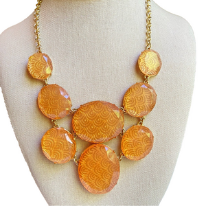 Bib style statement necklace with translucent peach acrylic segments in goldtone